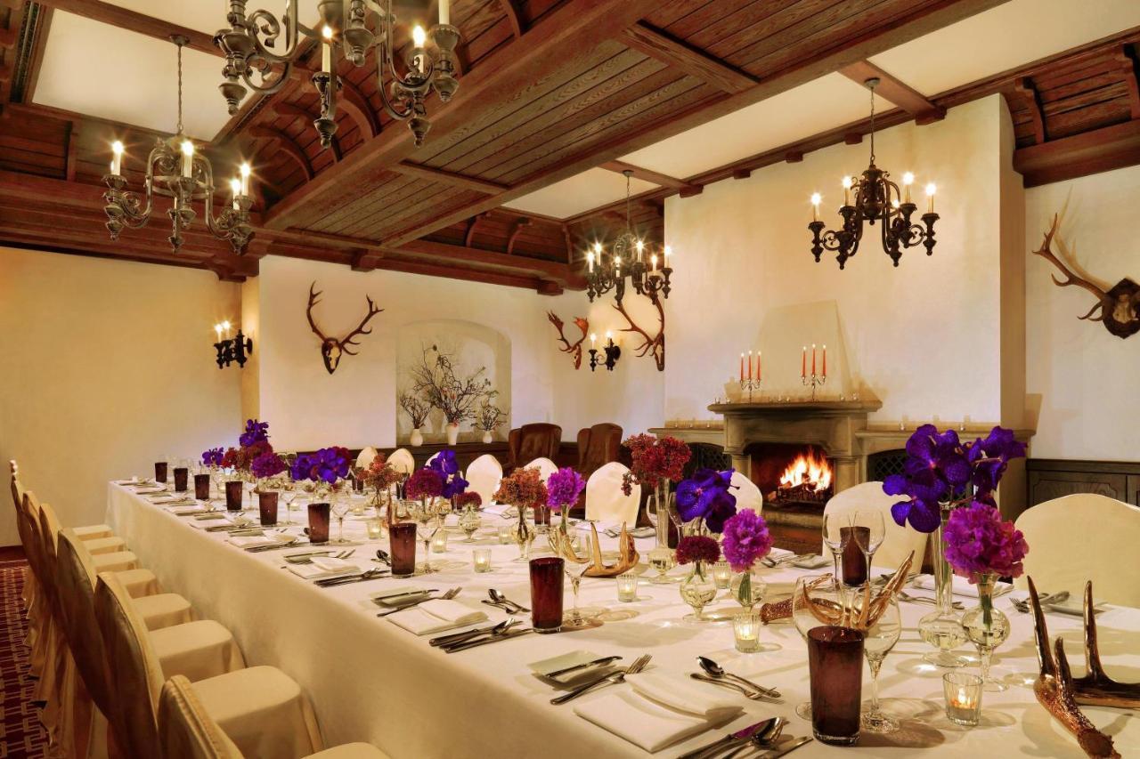 מלון The Westin Grand ברלין מראה חיצוני תמונה The photo depicts an elegantly arranged dining room. A long table is set with white tablecloths and neatly arranged place settings featuring glassware and cutlery. Vibrant purple flowers are placed in vases at intervals along the table, adding a pop 