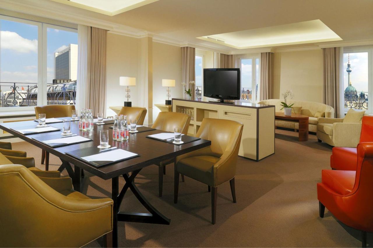 מלון The Westin Grand ברלין מראה חיצוני תמונה The photo depicts a well-appointed hotel or conference room. It features a large table surrounded by several beige chairs, suggesting it’s set up for a meeting or gathering. On the table, there are water bottles and notepads, indicating preparation f